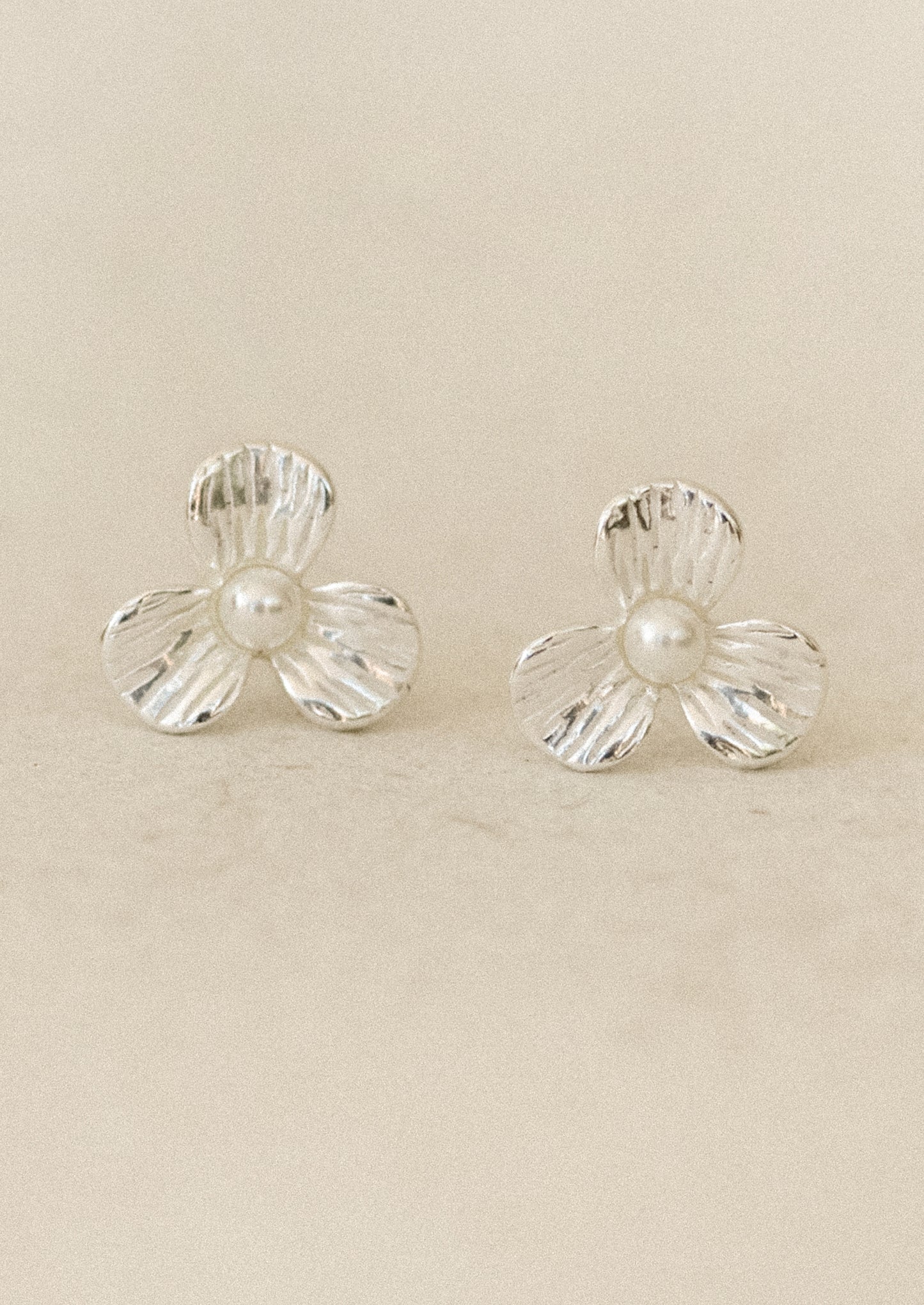 A pair of sterling silver 3-petal flower studs with a pearl center.