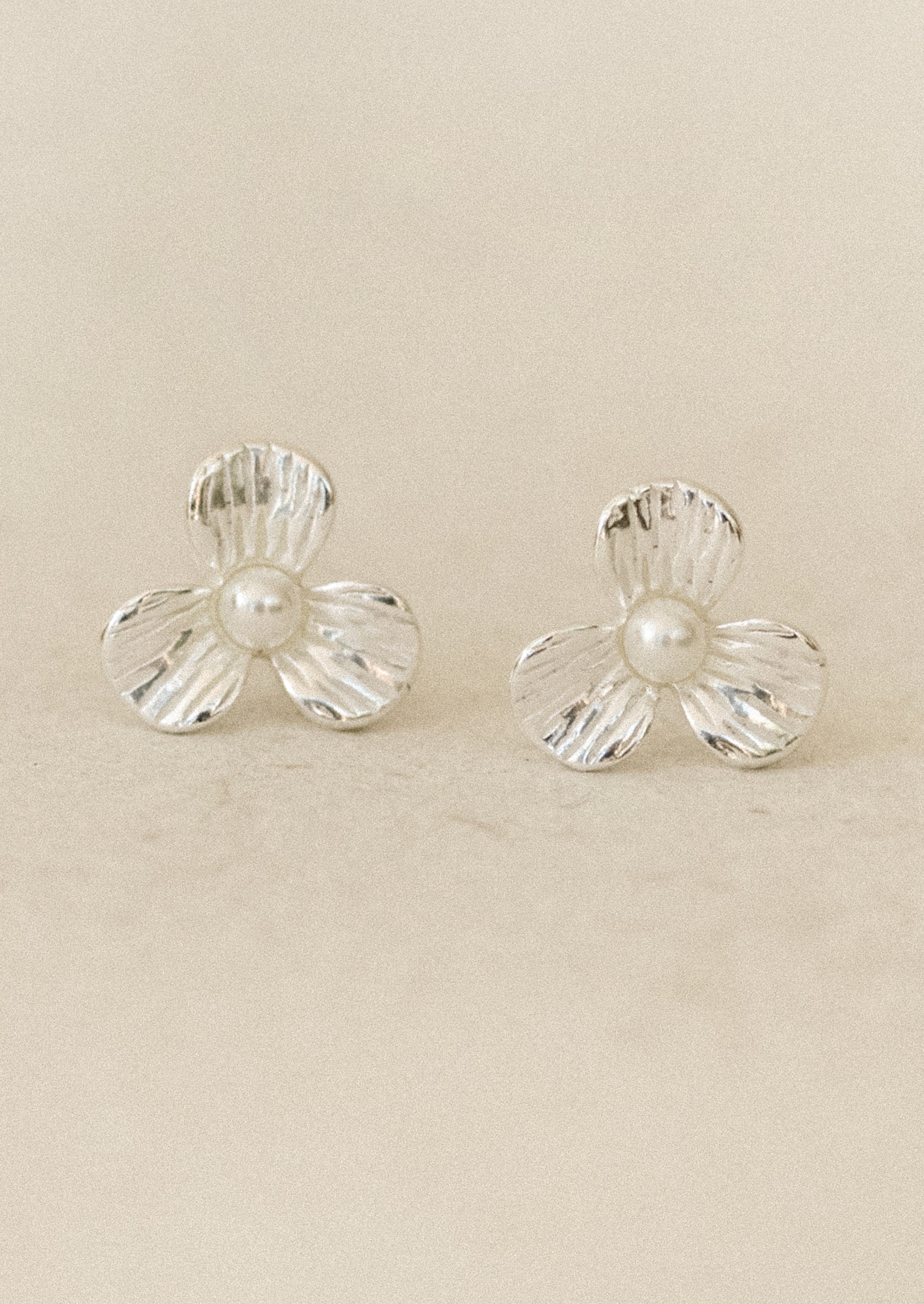 A pair of sterling silver 3-petal flower studs with a pearl center.