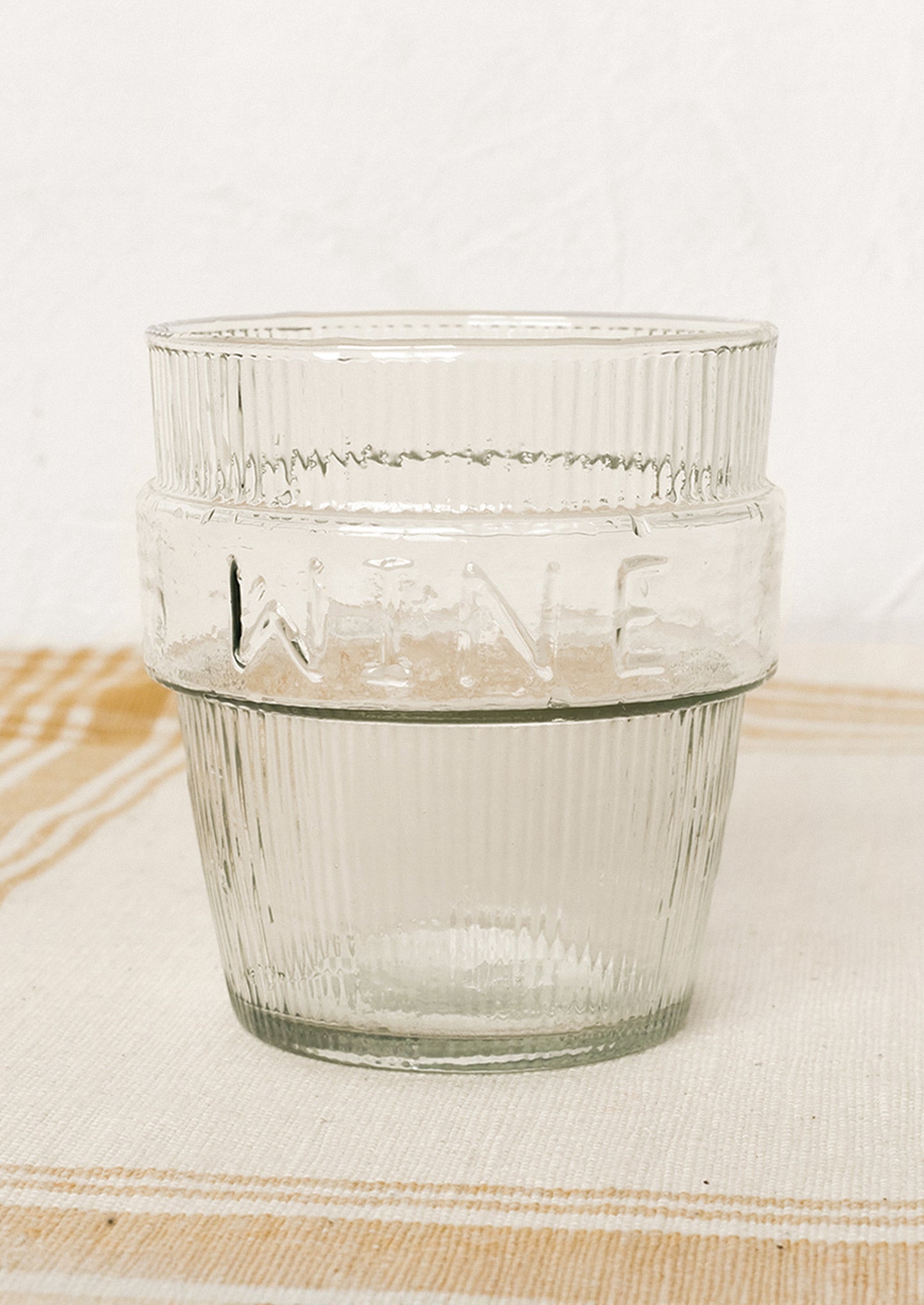 A short ribbed clear glass cup labeled "wine".