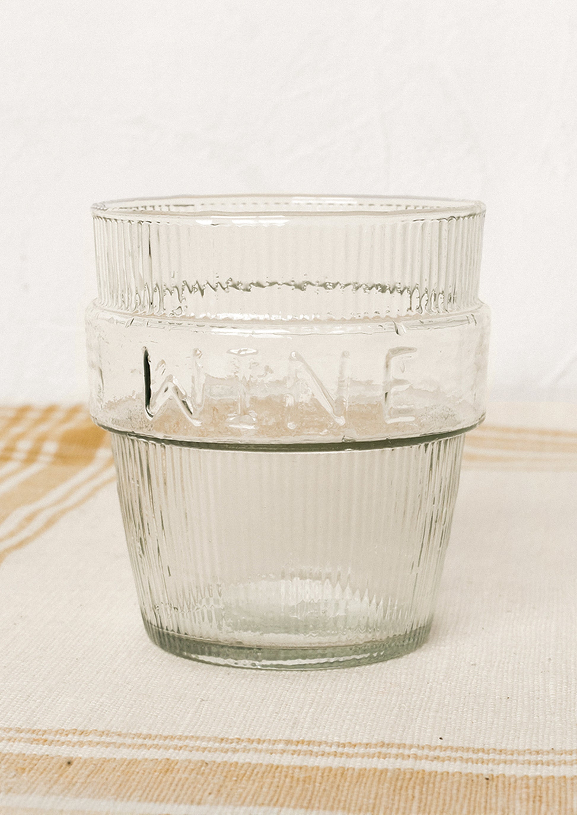A short ribbed clear glass cup labeled "wine".