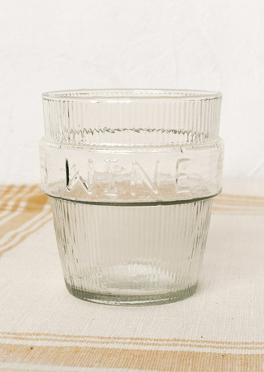A short ribbed clear glass cup labeled "wine".