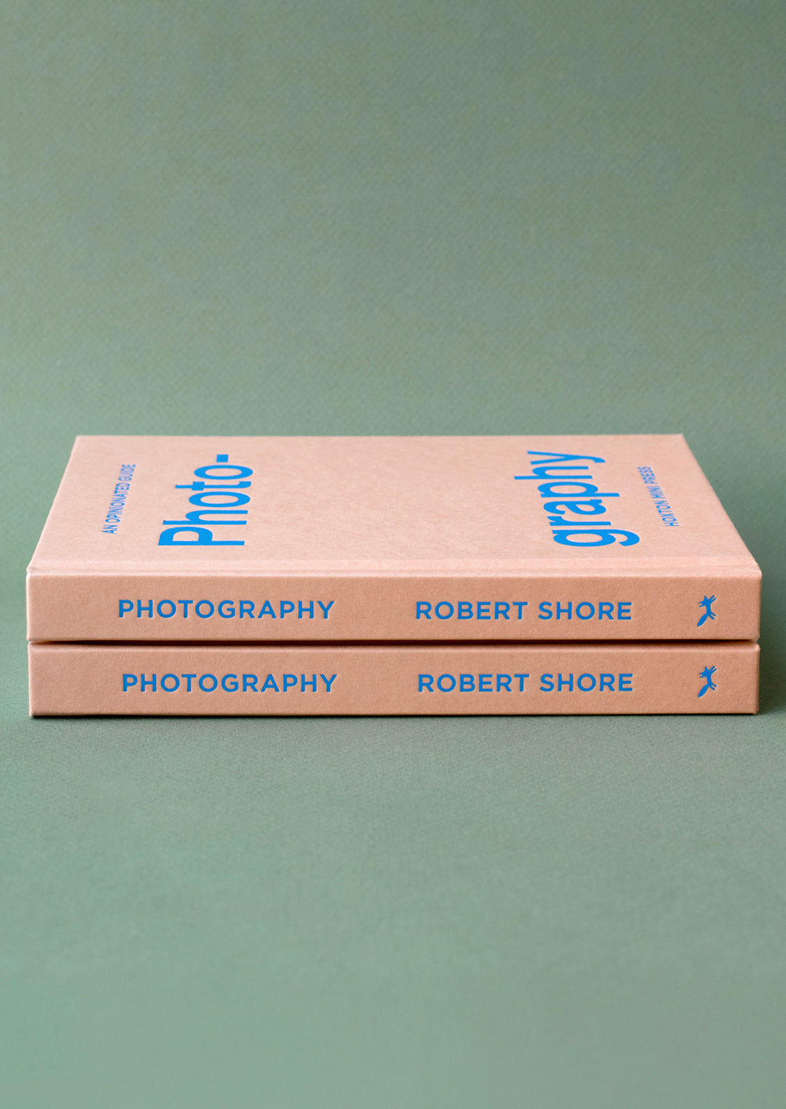 A pink hardcover book with blue lettering titled "An Opinionated Guide To Photography".