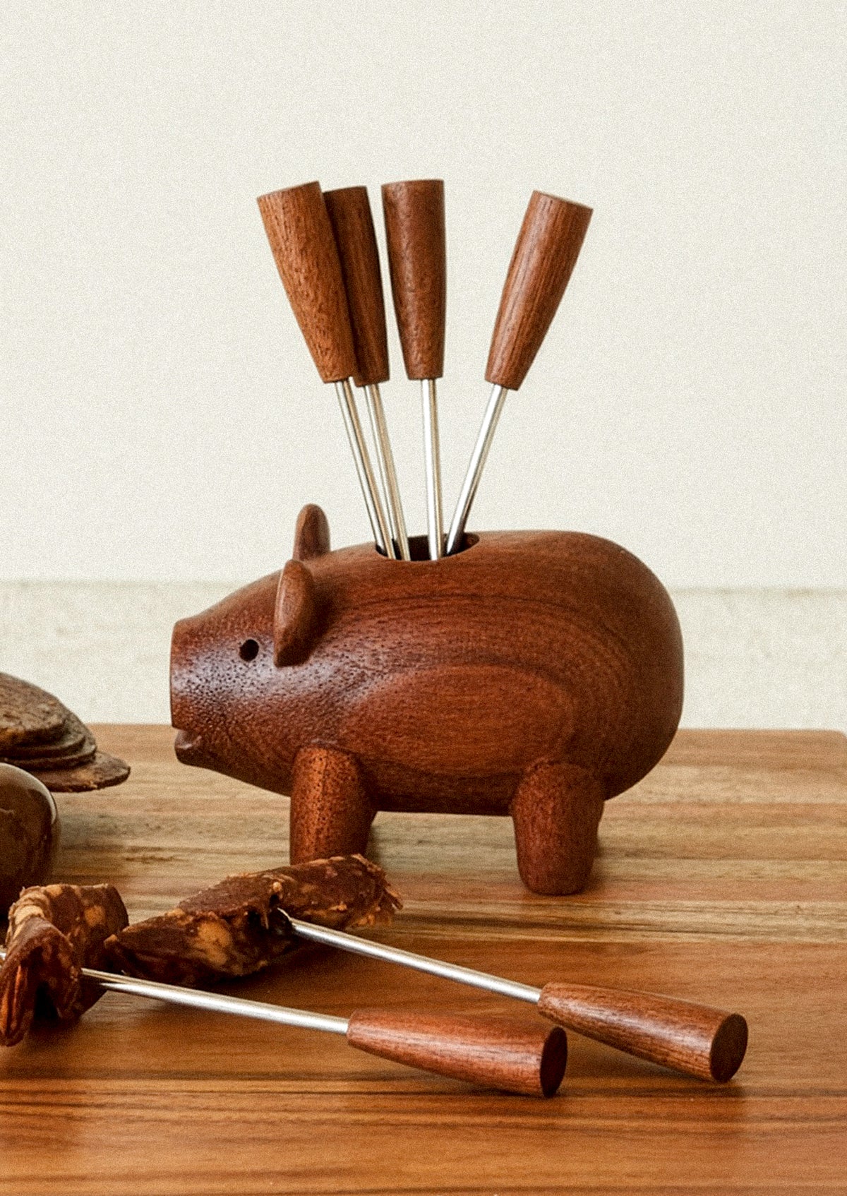 Wooden pig-shaped holder with metal skewers on a wooden surface