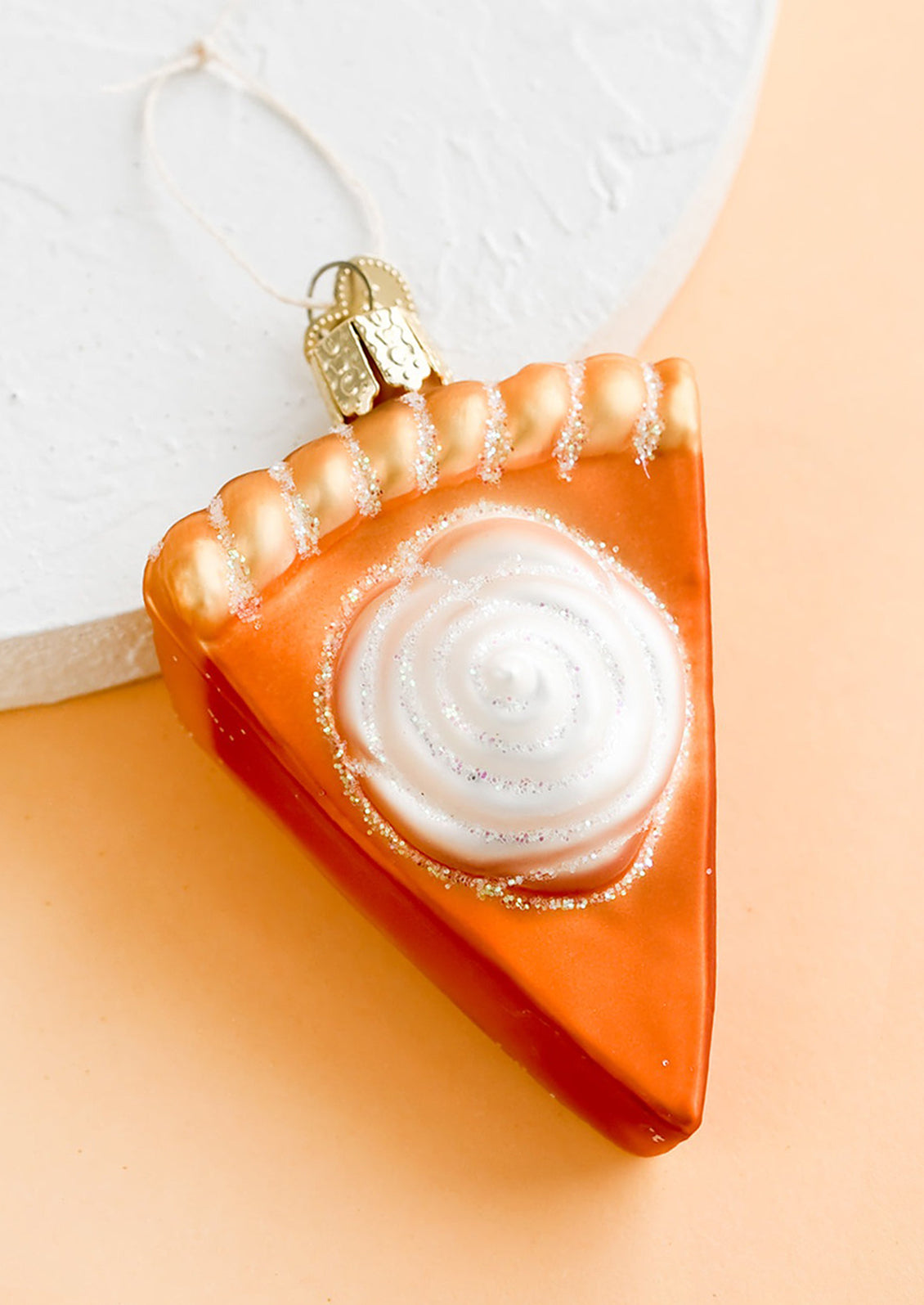 A glass ornament in shape of pumpkin pie slice.