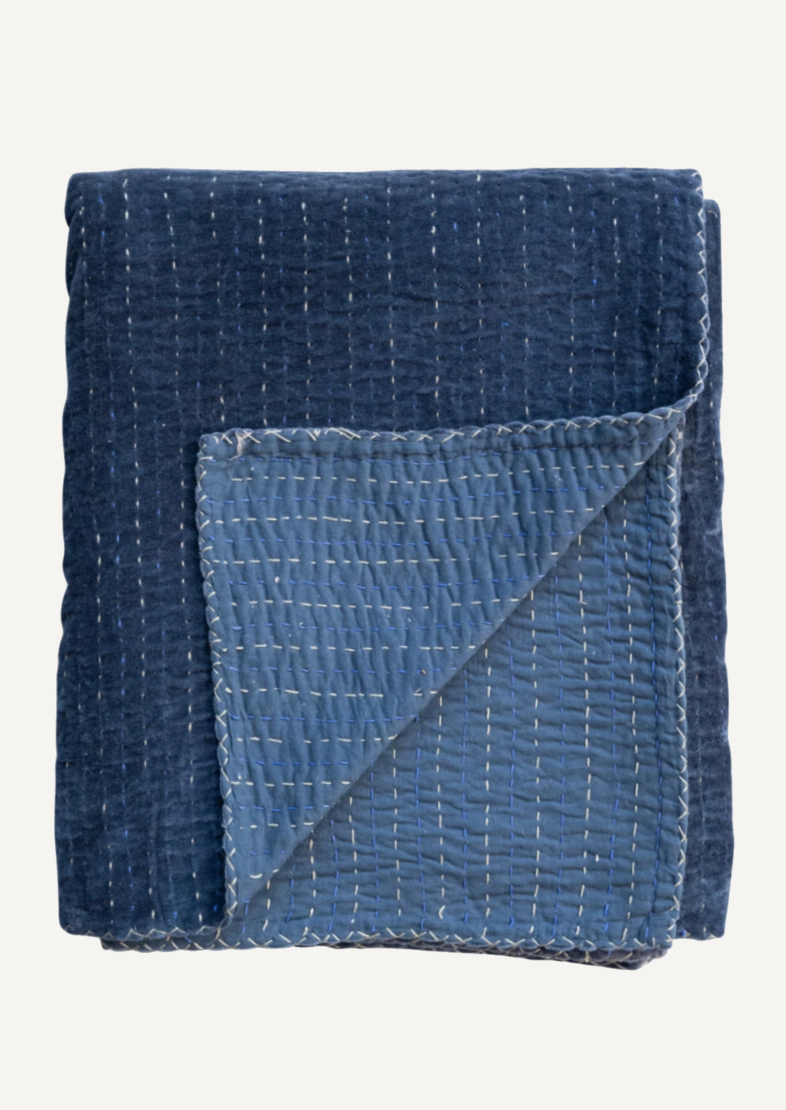 An indigo blue velvet throw blanket with blue and white kantha stitched stripes throughout.