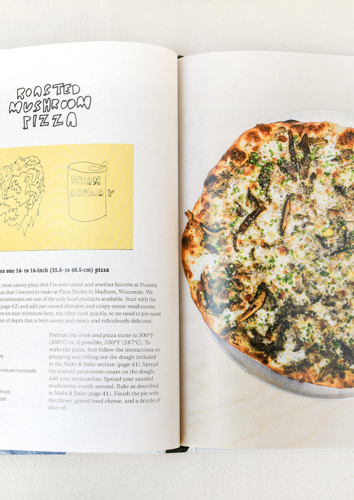 A book open on a table with a recipe for roasted mushroom pizza.