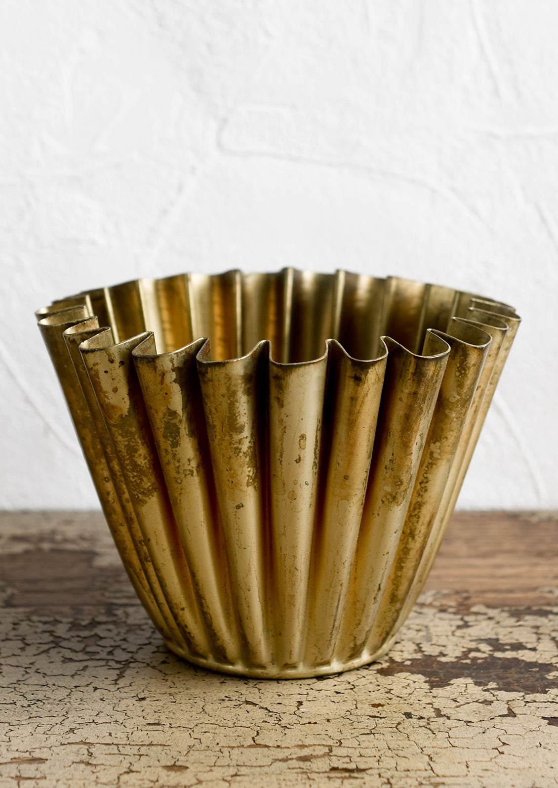 A pleated metal planter in distressed brass finish.