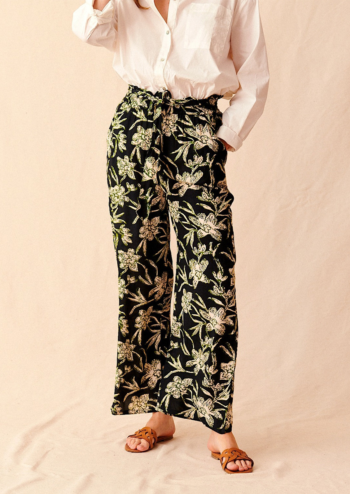 A pair of flowy pants in black with all over cream and green floral print.