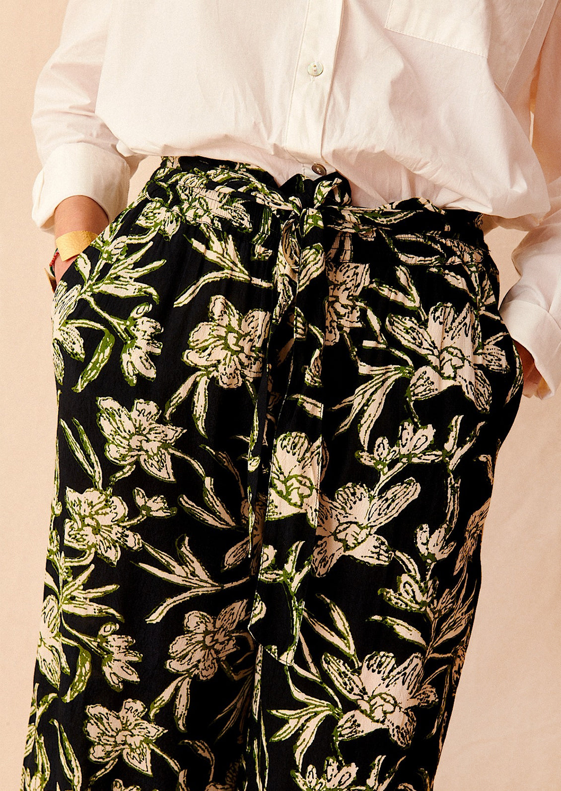 A pair of flowy pants in black with all over cream and green floral print.