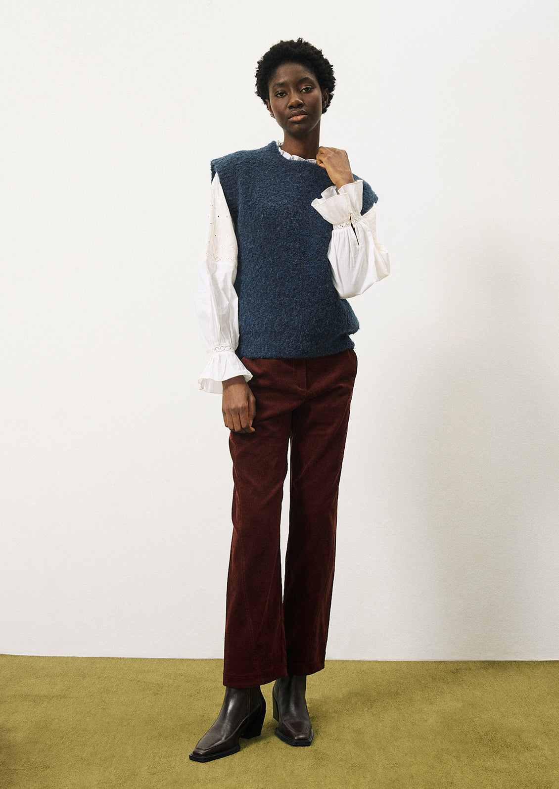 A woman wearing a cap sleeve sweater vest in marled blue knit with boucle texture.