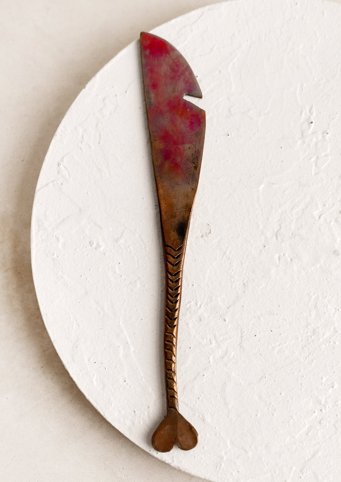 A copper knife with fish tail handle and oxidized finish.