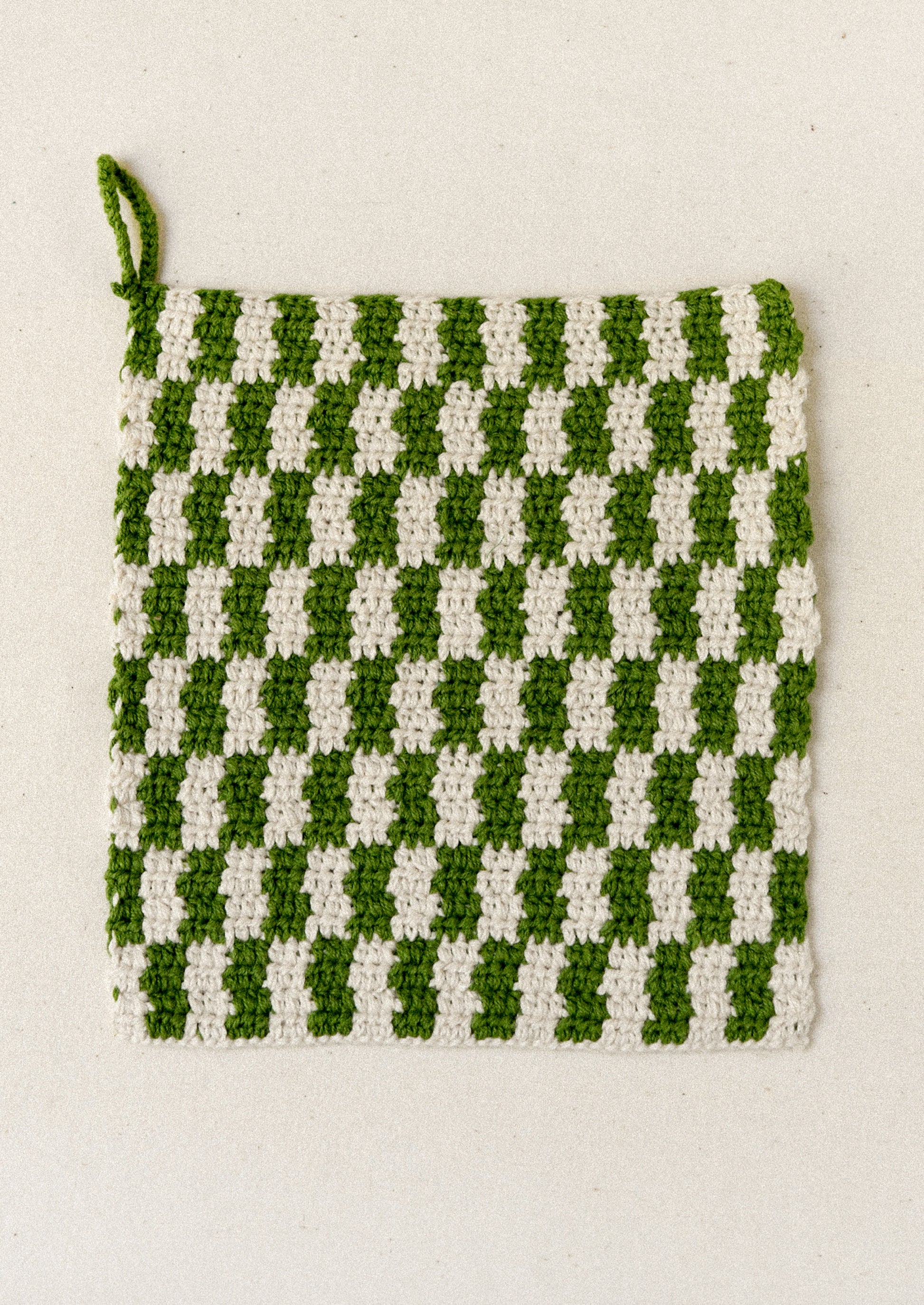A green plaid crocheted potholder.