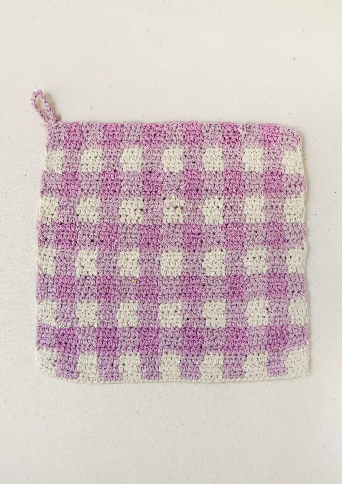 A pink plaid crocheted potholder.