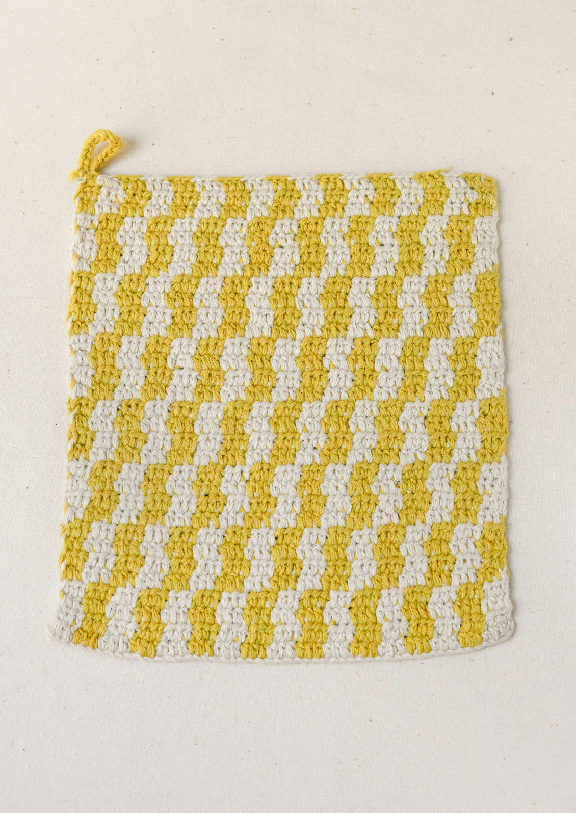 A yellow plaid crocheted potholder.