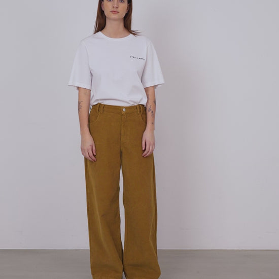 A woman wearing a pair of ochre colored wide leg corduroy pants.