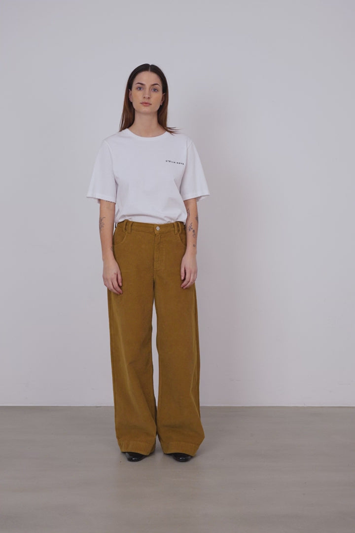 A woman wearing a pair of ochre colored wide leg corduroy pants.