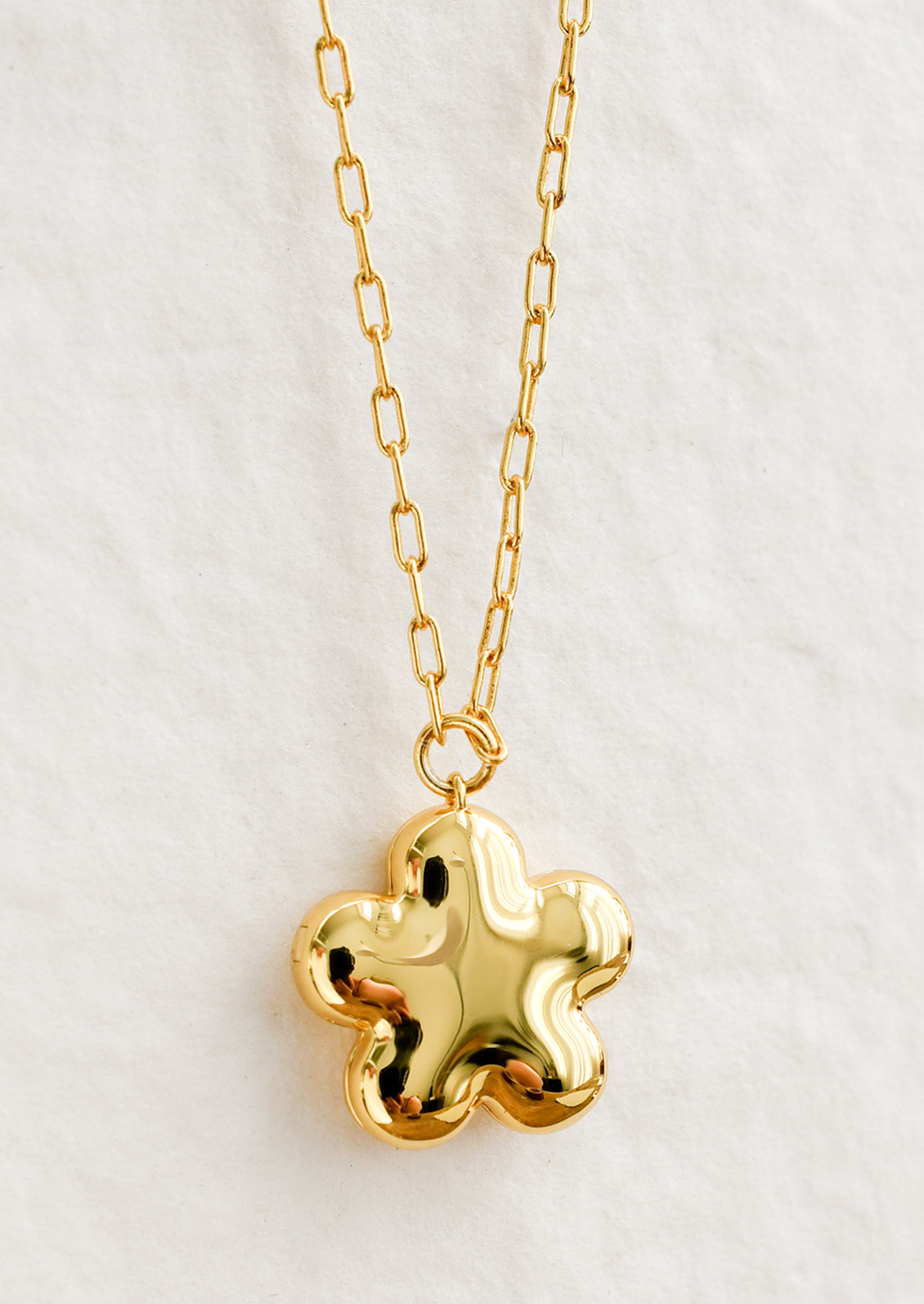 A flower shaped necklace in gold with a puffy look.