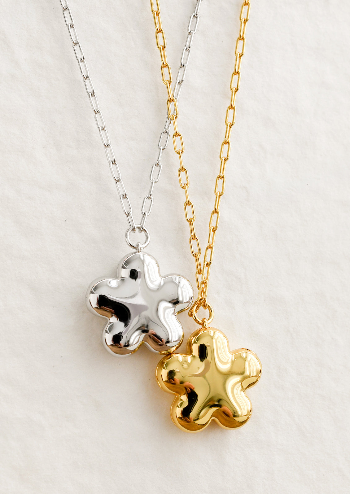 Flower shaped necklaces in gold and silver with a puffy look.