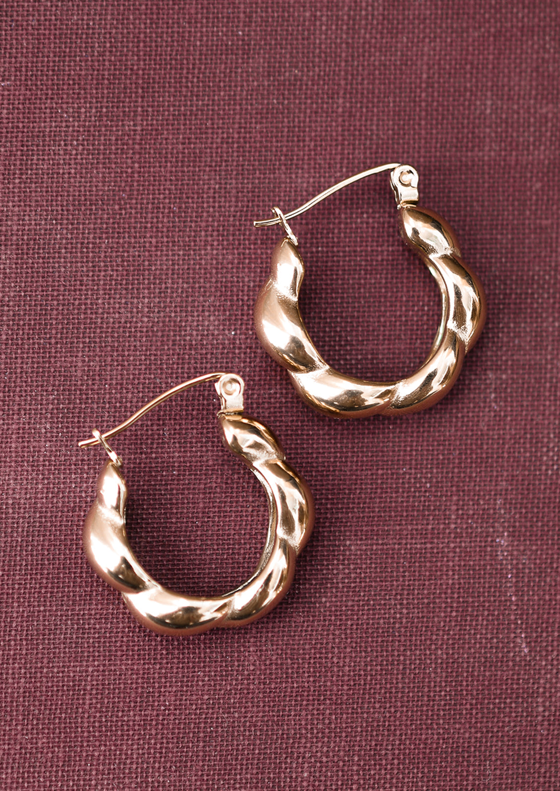 A pair of gold hoop earrings with puffy twist texture.