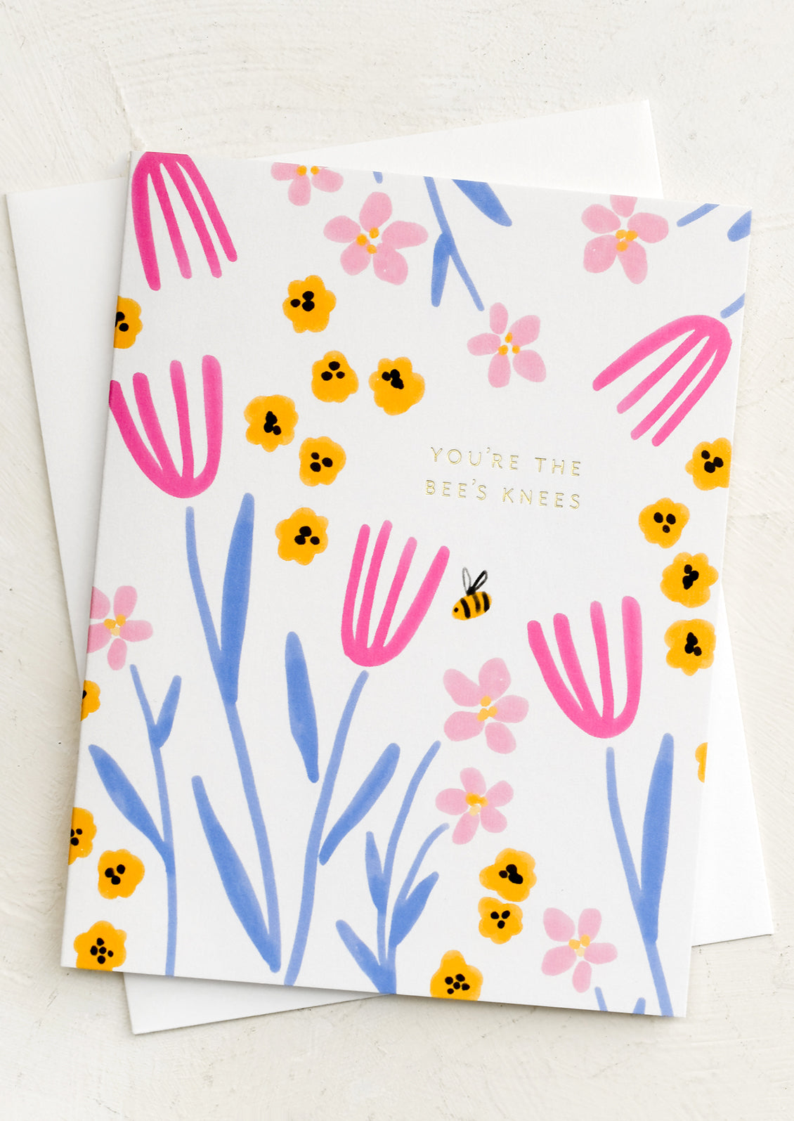 A floral print greeting card with gold text reading "You're The Bees Knees".