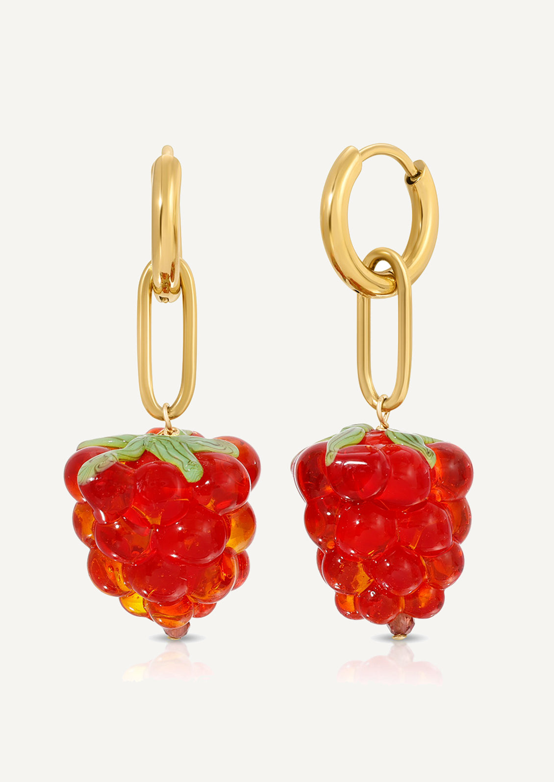 A pair of gold earrings with glass raspberry charm.