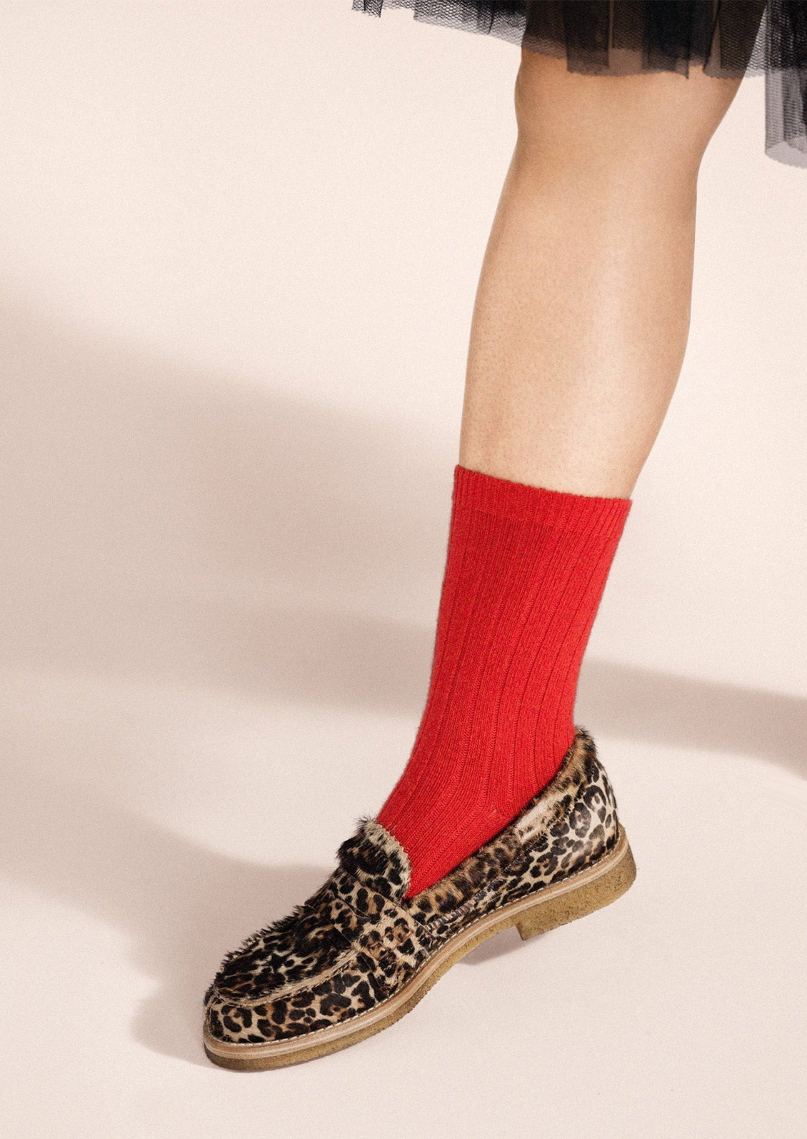 A person wearing a pair of soft red ribbed socks.