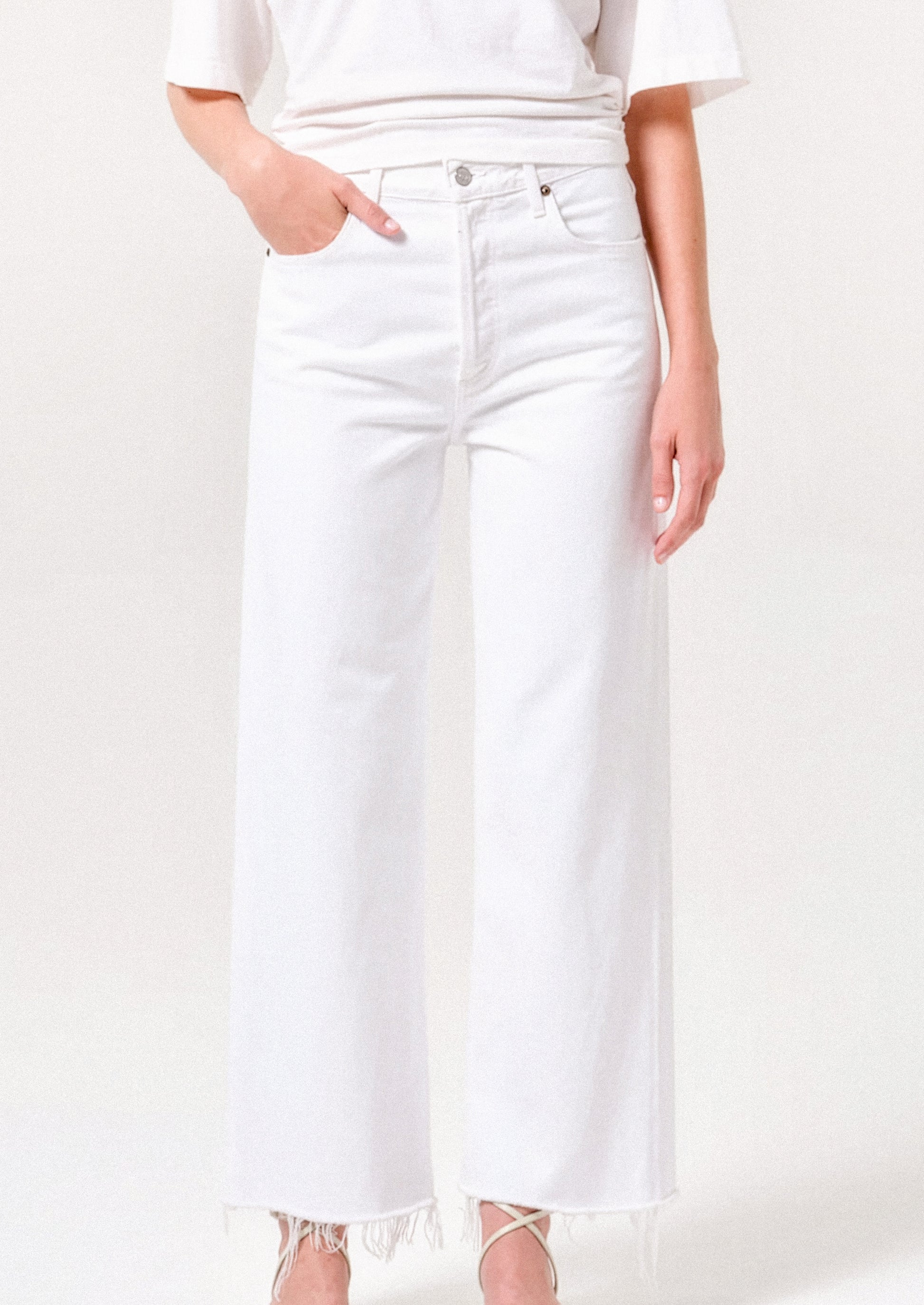 Person wearing white jeans and a white top on a plain background