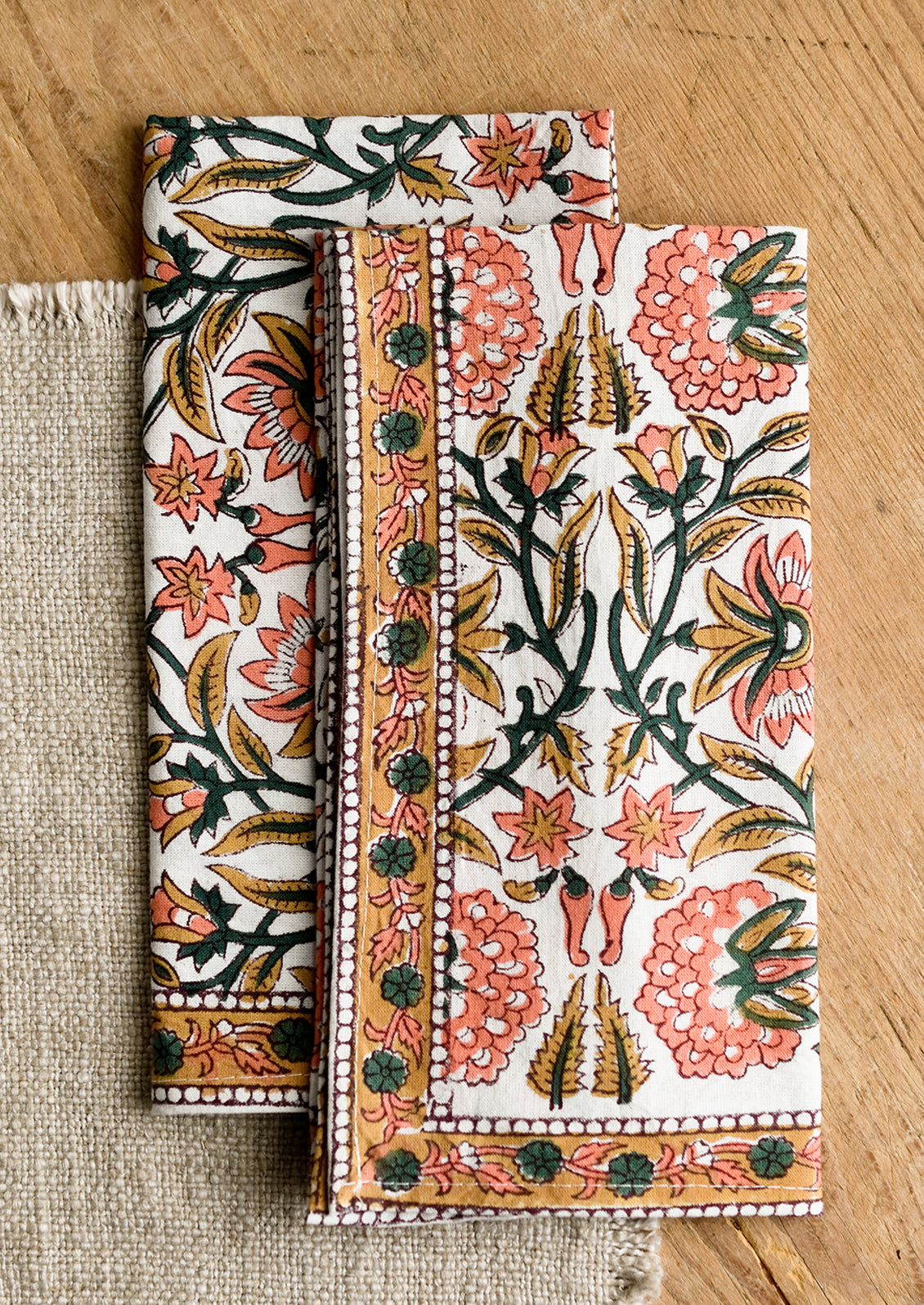 A set of two block printed napkins in pink, emerald and brown print.
