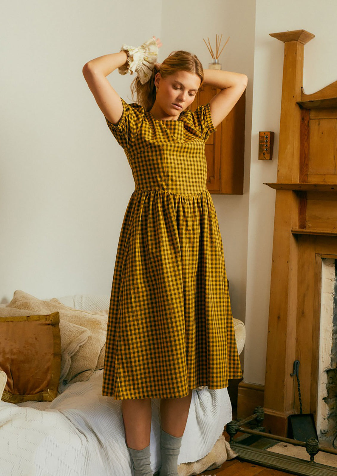 A woman wearing a brown and mustard gingham short sleeve dress.