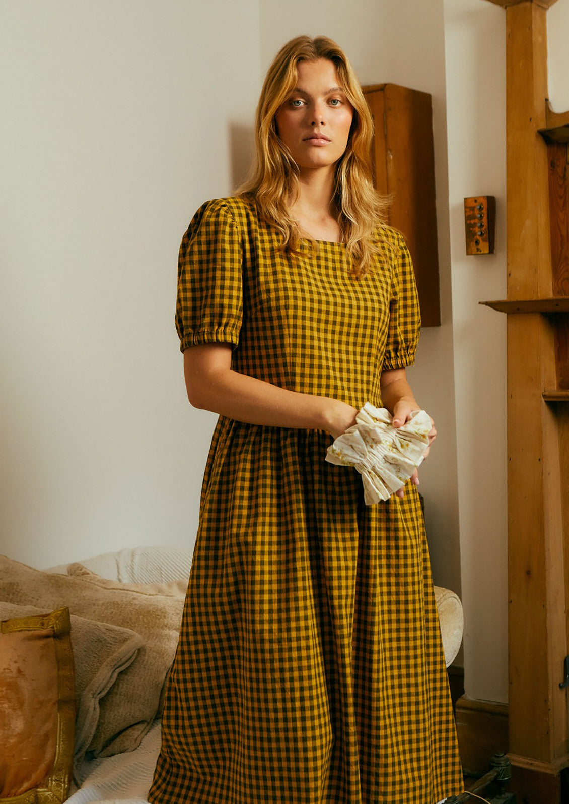 A woman wearing a brown and mustard gingham short sleeve dress.