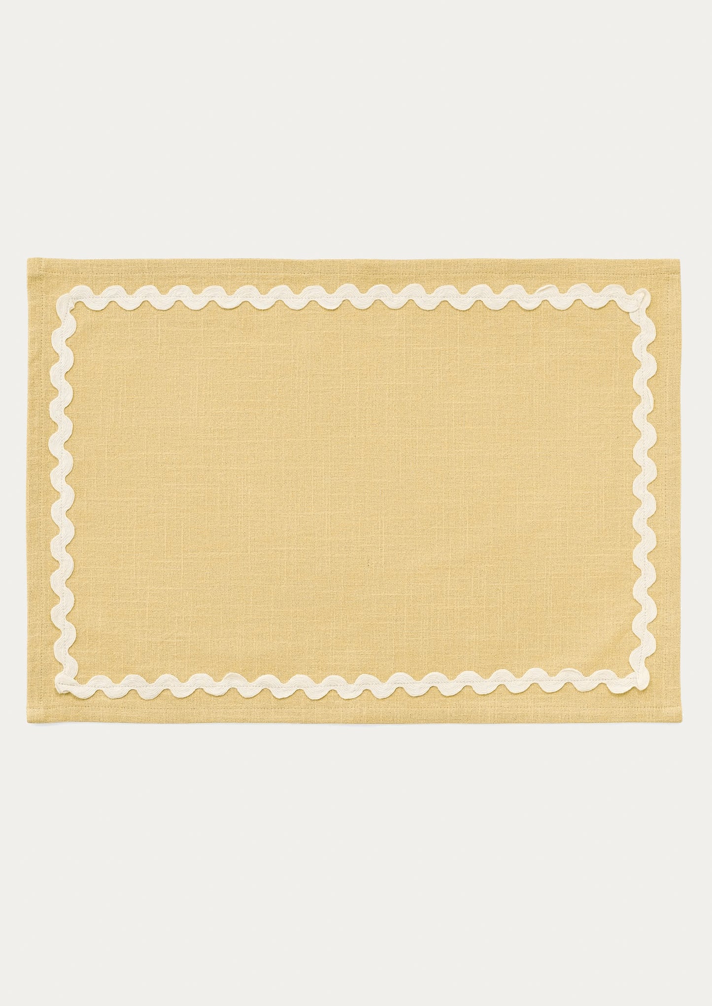 A butter yellow placemat with white ricrac trim border.