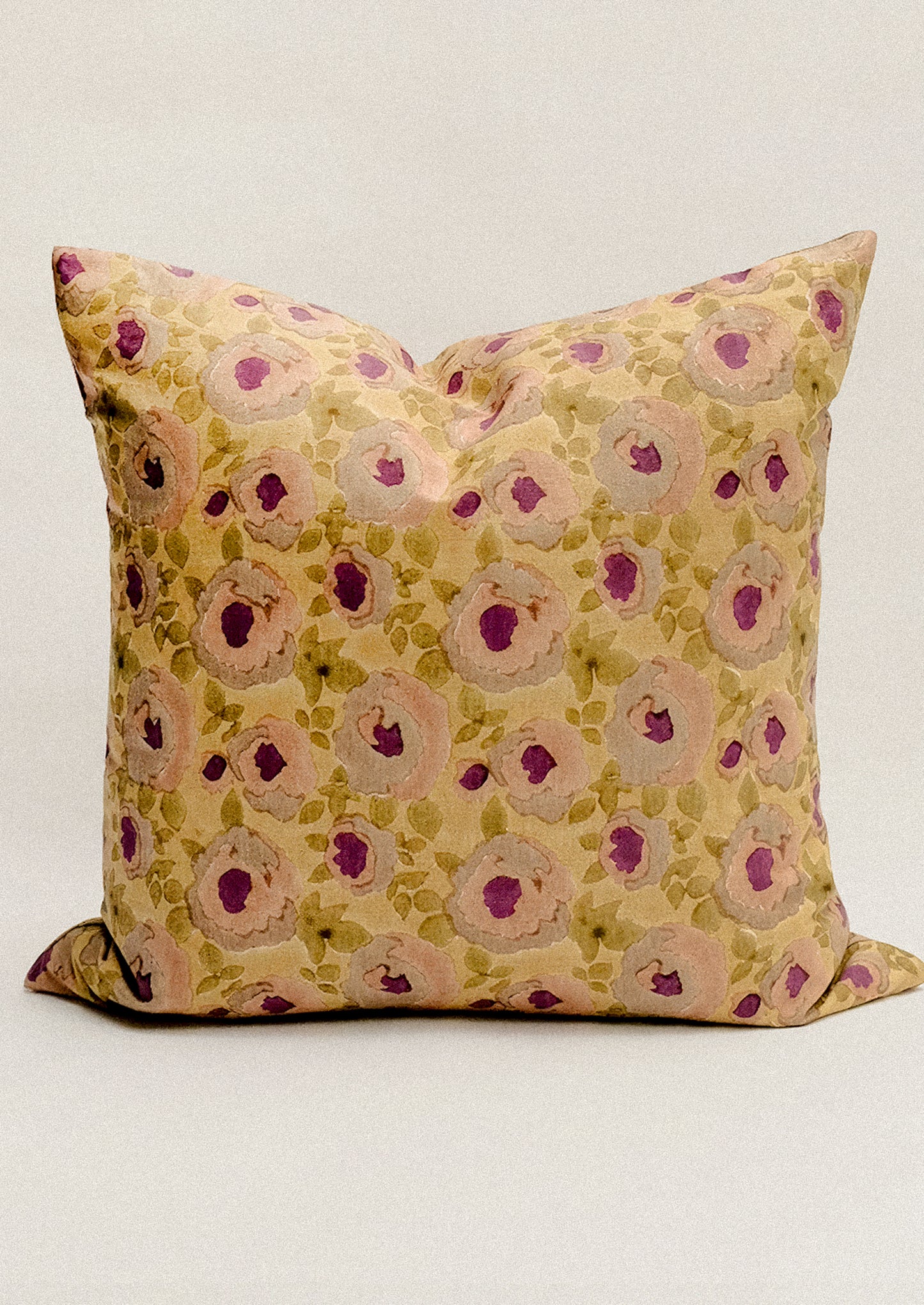 A block printed throw pillow in ochre and pink floral print.