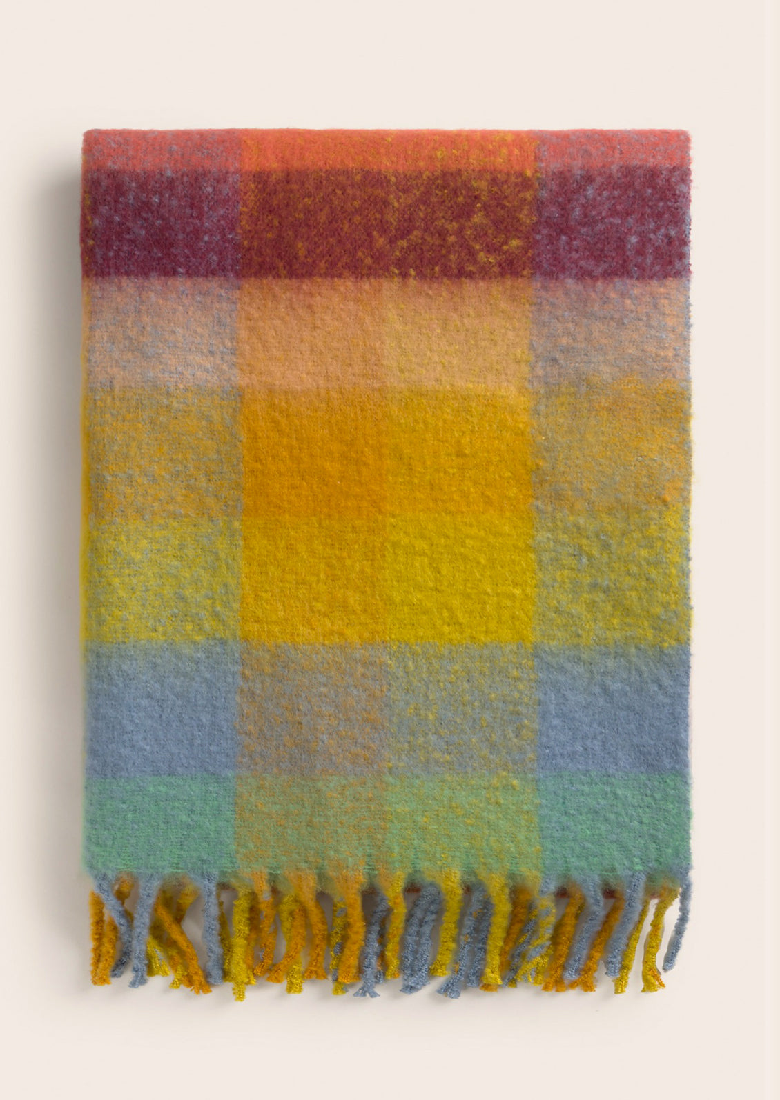 Multicolored checkered blanket with frayed edges on a light background