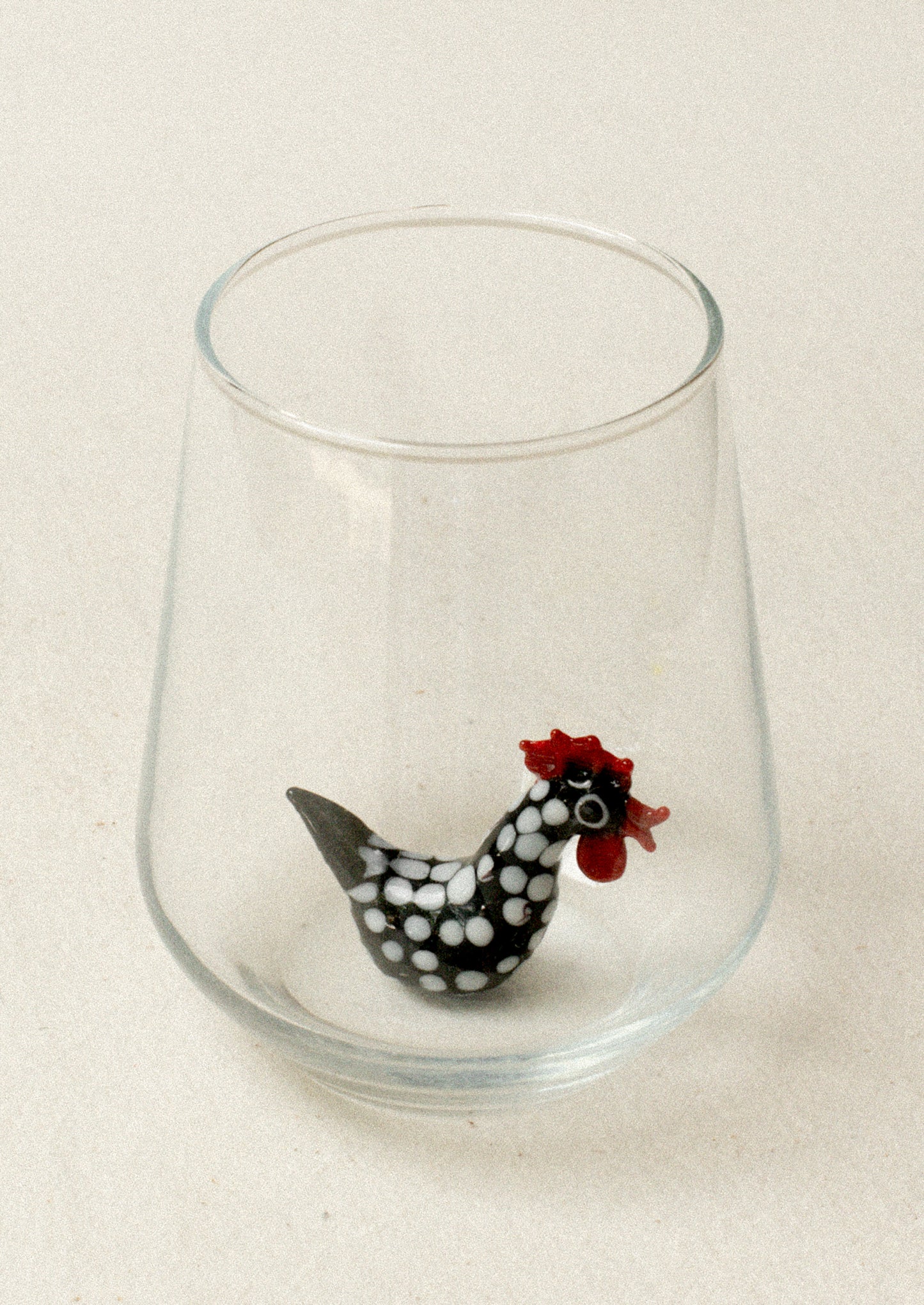 A glass with lampwork rooster detail at bottom of inside glass.