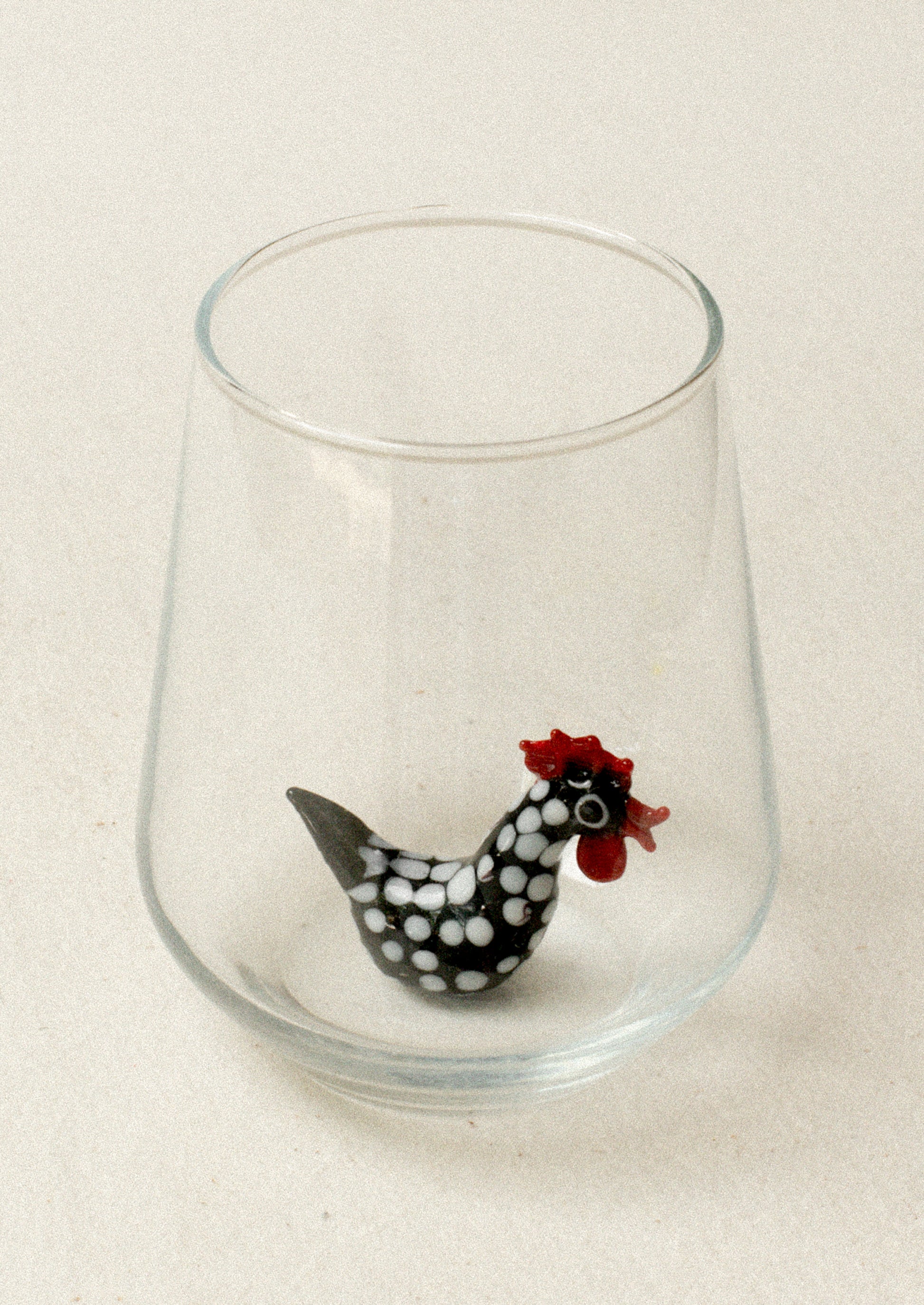 A glass with lampwork rooster detail at bottom of inside glass.
