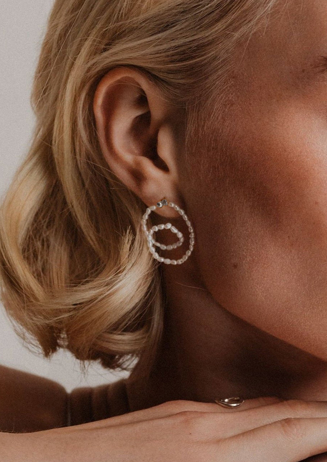 A pair of looped beaded pearl earrings with sterling silver ball post.