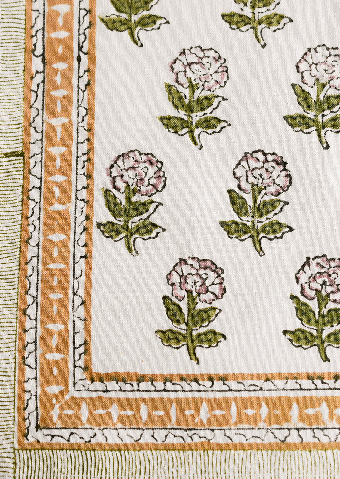 A block printed placemat in floral print in green and purple with mustard border.