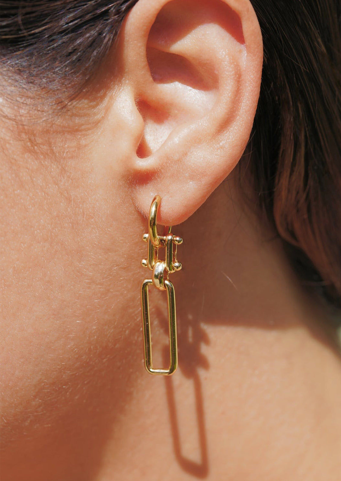 A pair of gold earrings with linked design.