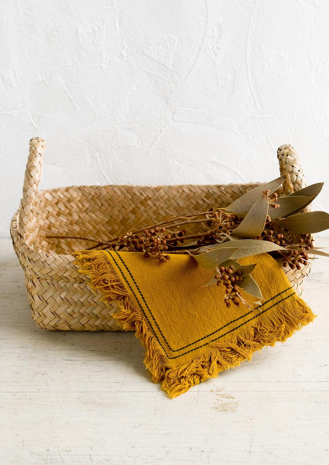 A rectangular seagrass basket with rolled top rim and side handles.