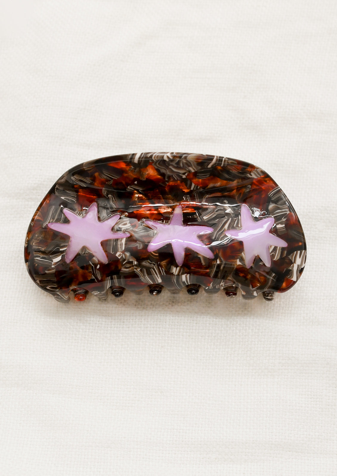 A hair claw in brown tortoise with translucent purple starburst design.