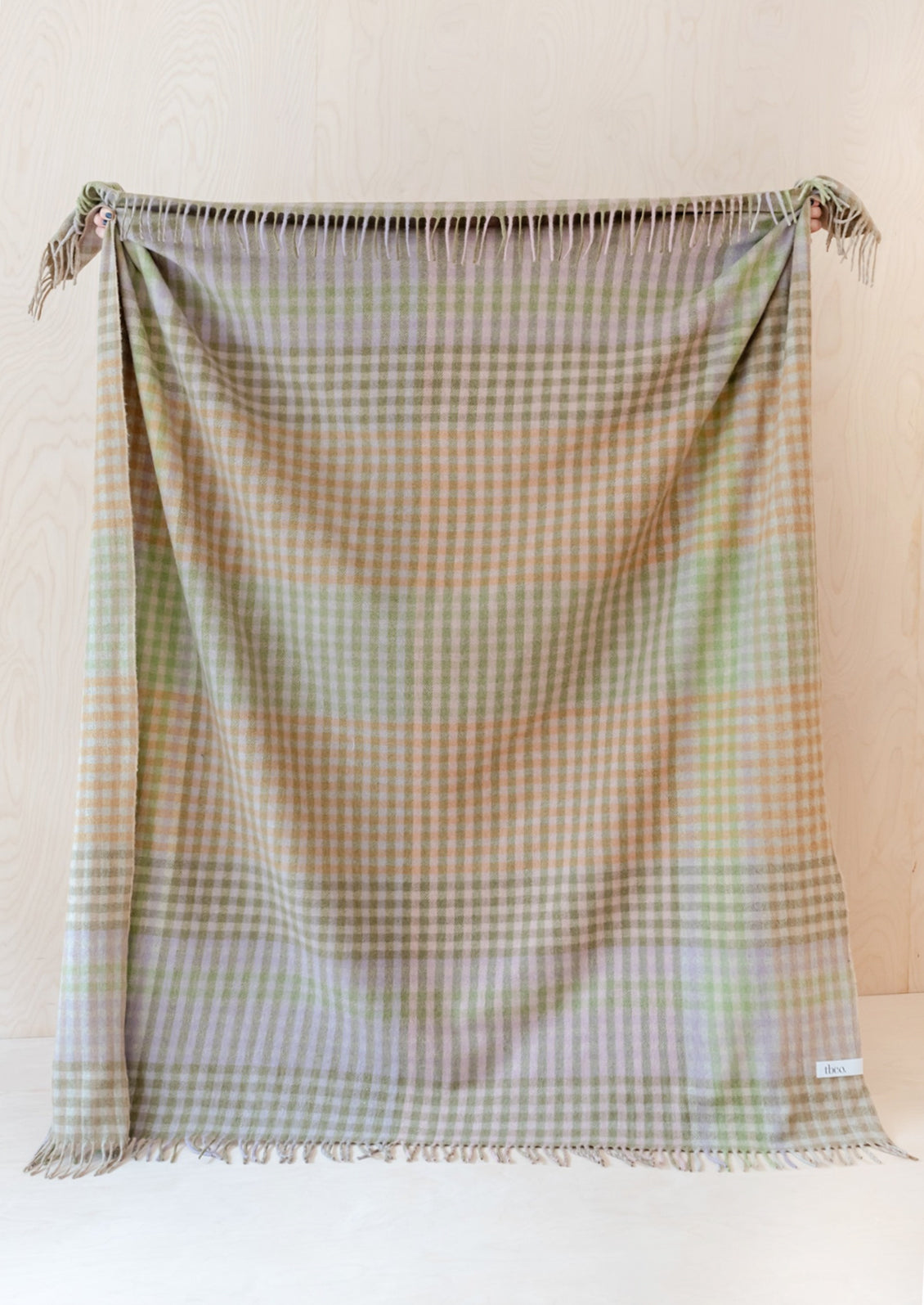 A gingham check print throw in mix of pastel and earthy greens and browns.