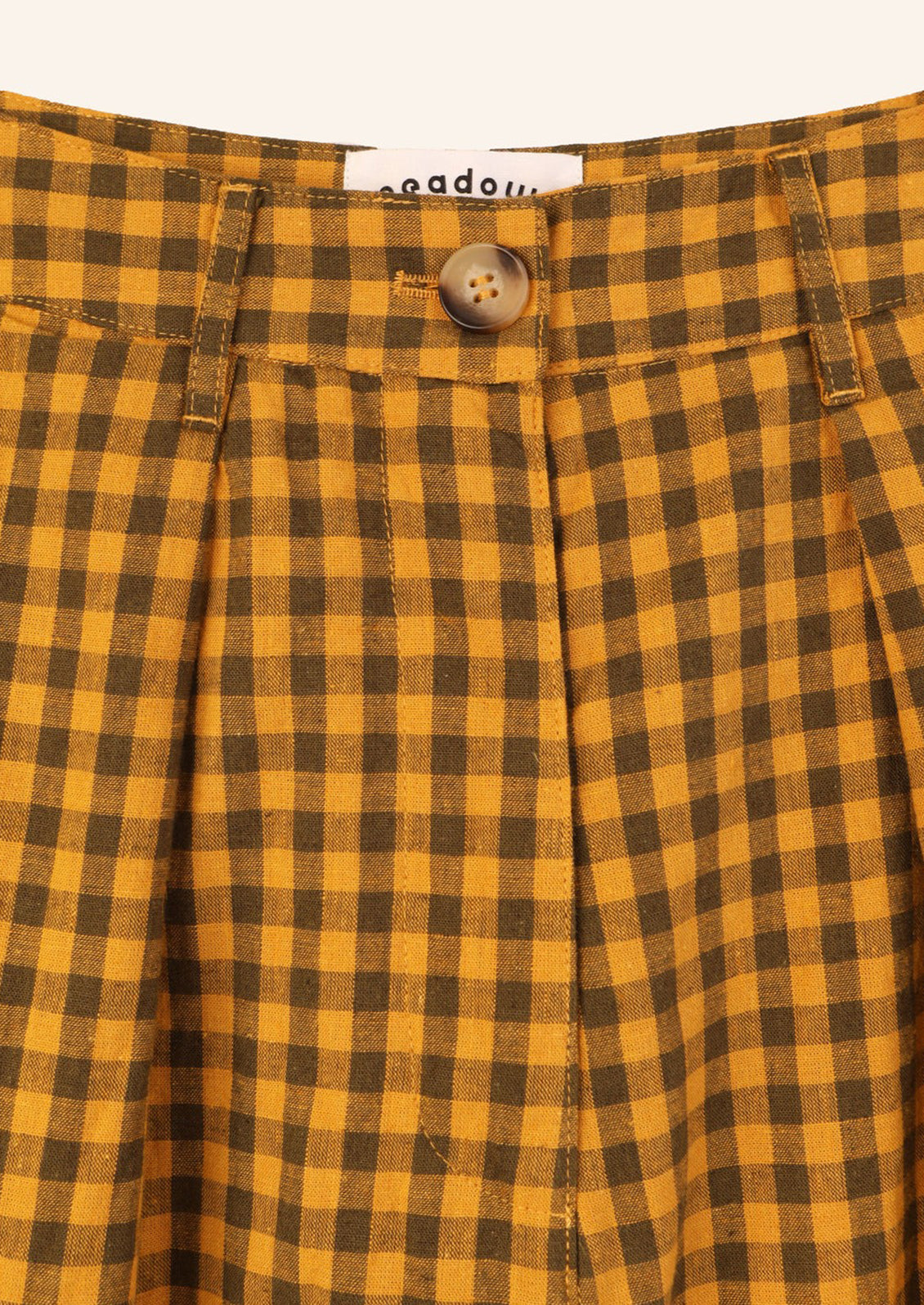 A pair of long, pleat front shorts in brown and mustard gingham.