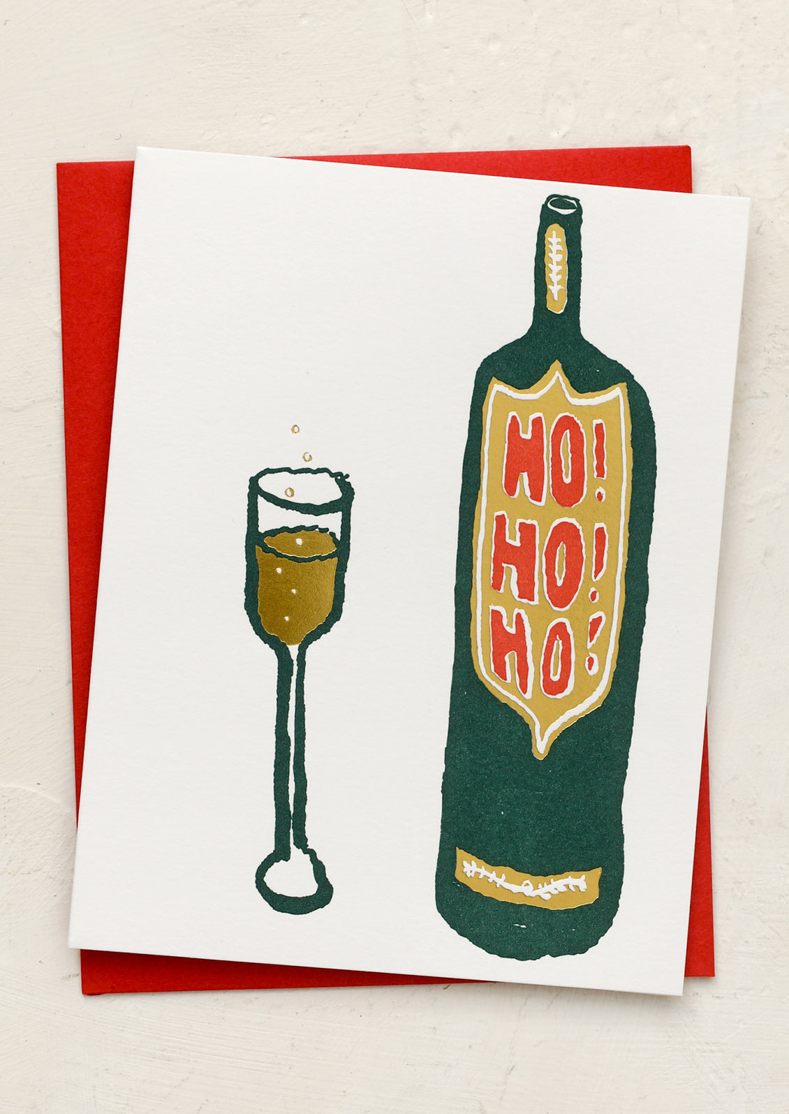 A greeting card with illustration of glass of champange next to bottle, text on bottle reads "Ho Ho Ho!".
