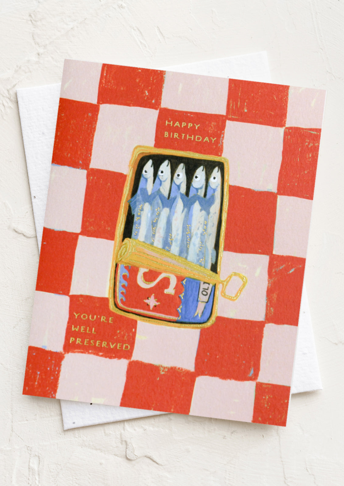 A red and pink checkered card with illustration of tin of sardines, texts reads "Happy Birthday, you're well preserved".