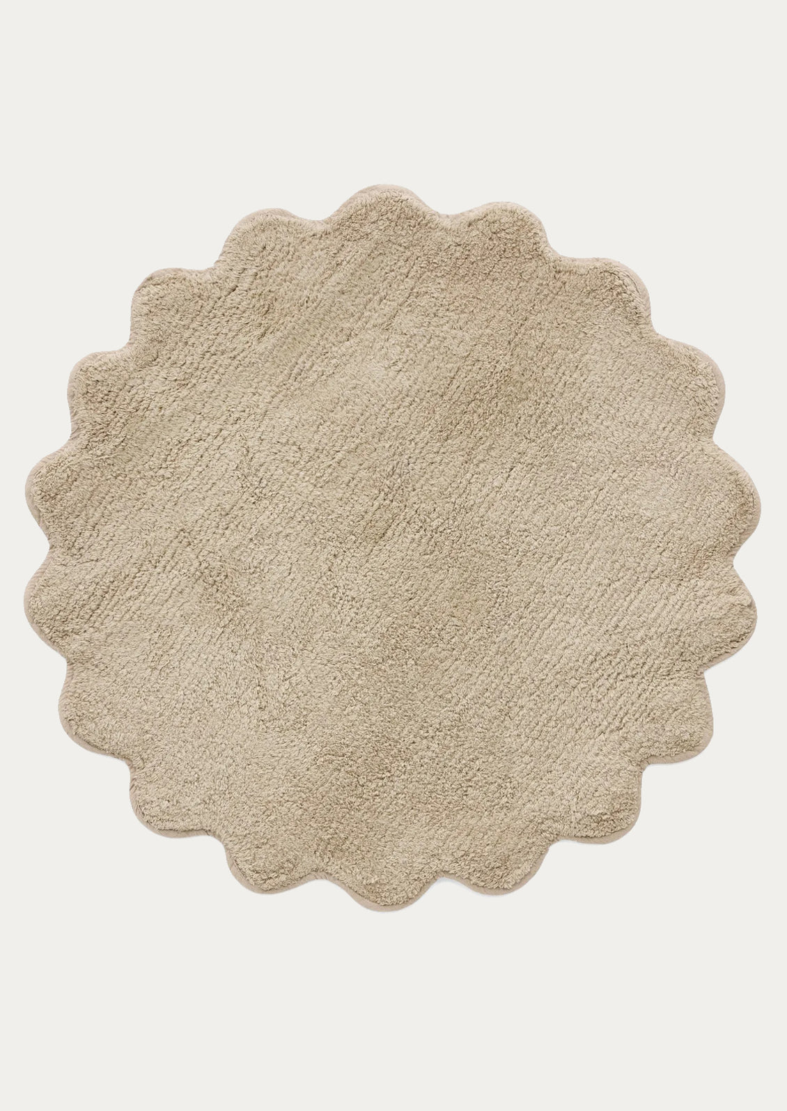 A round bathmat with scalloped edges in taupe.