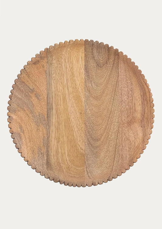 A round wooden serving board with a scalloped edge.