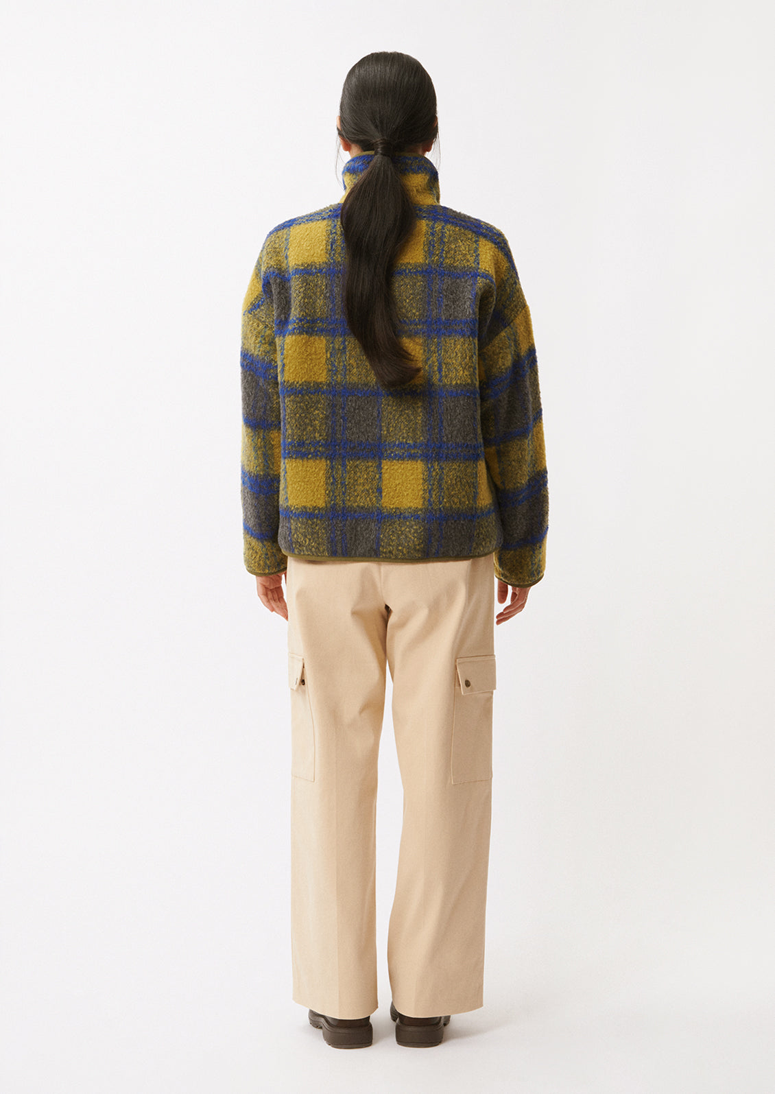 A woman wearing a fleece pullover in olive and cobalt blue plaid pattern.