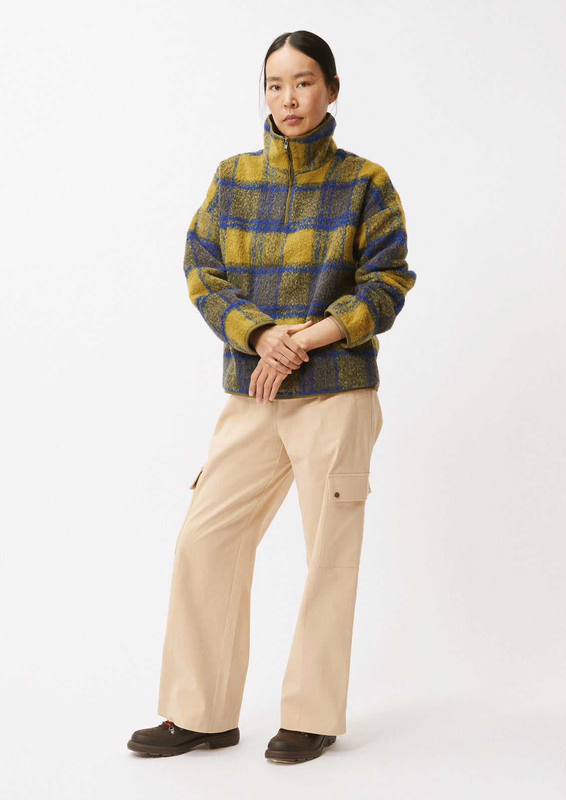 A woman wearing a fleece pullover in olive and cobalt blue plaid pattern.