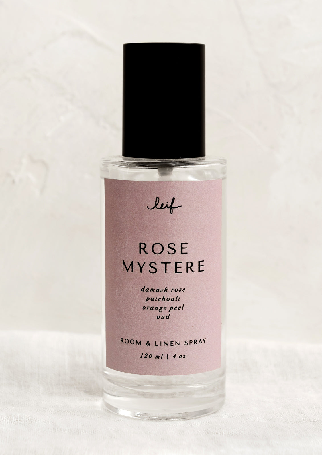 A room spray bottle with printed text on pink label.