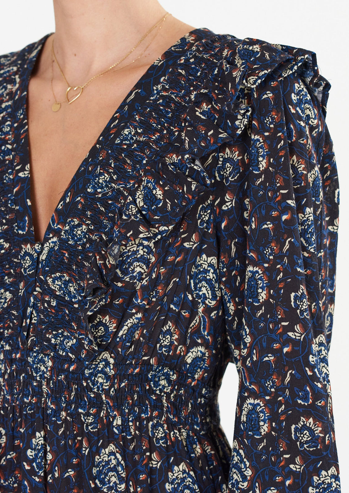 A long sleeve maxi dress with ruffled v-neck in black with blue, white and rust block print pattern.